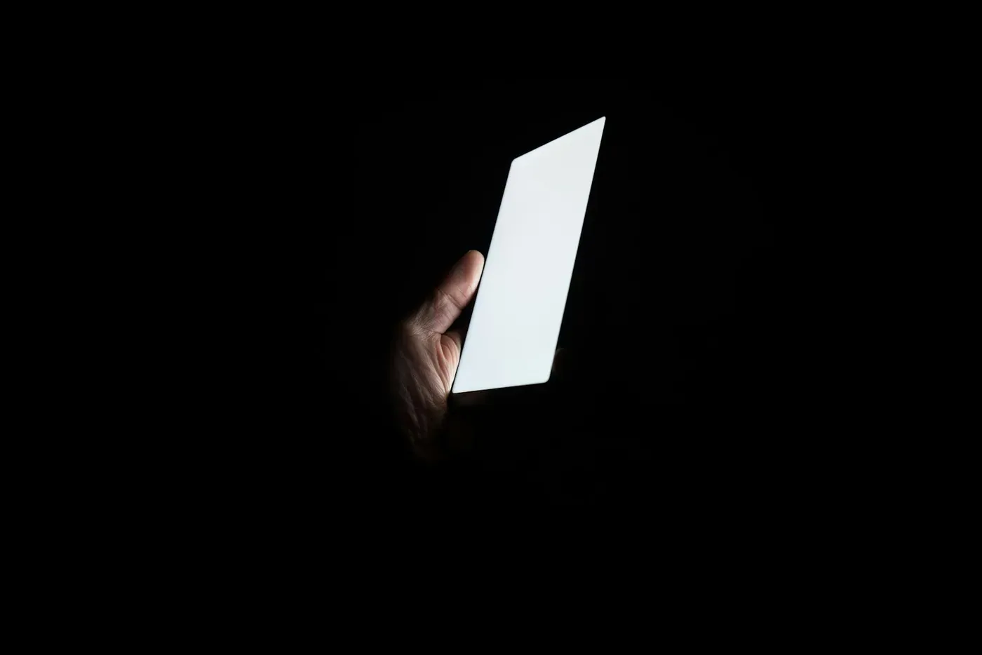 Smartphone leuchtet in völliger Dunkelheit in einer Hand