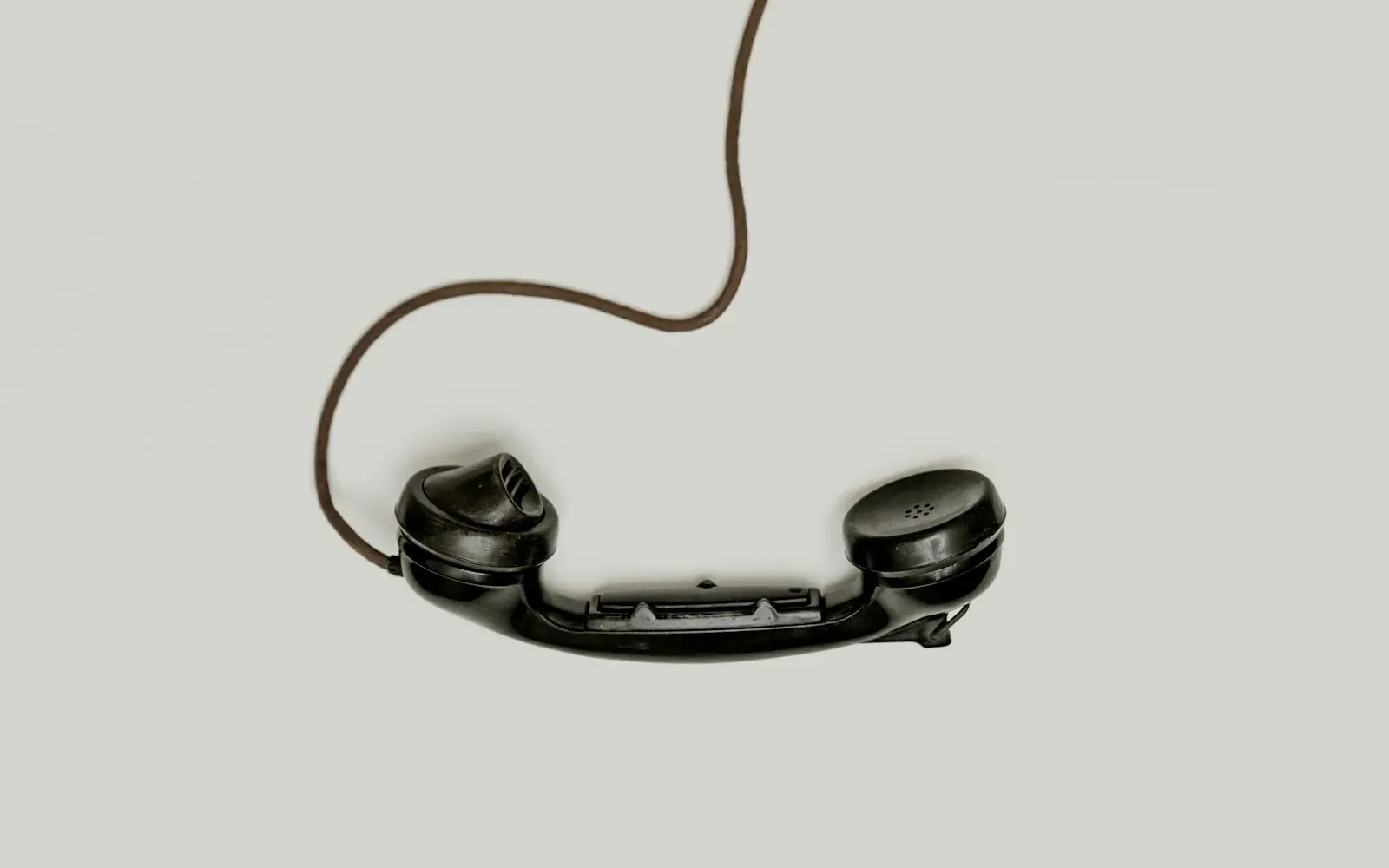 Schwarzer Telefonhörer mit Spiralkabel auf hellem Hintergrund