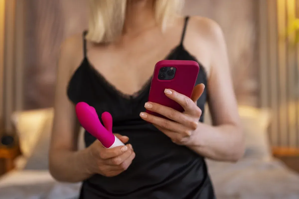 Frau liegt mit dem Smartphone im Bett und wartet auf einen Anruf