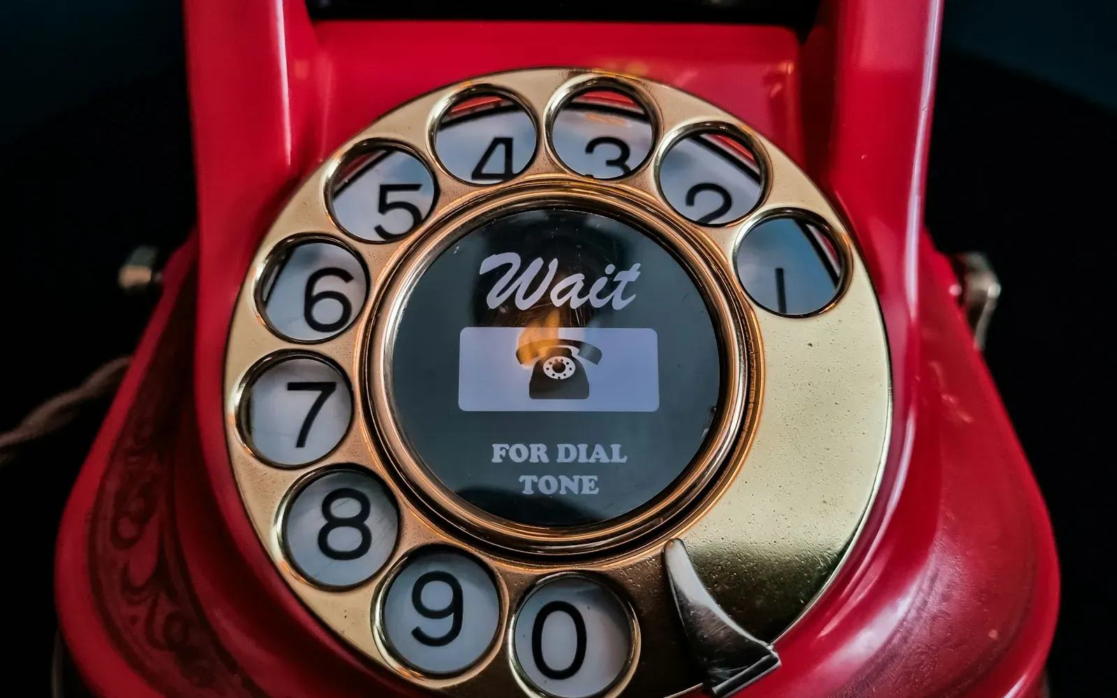 Rotes Wählscheibentelefon mit goldener Wählscheibe vor dunklem Hintergrund – Telefonsex oder Sexchat im Vergleich