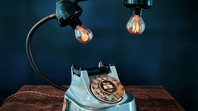 Altes Wählscheibentelefon unter warm leuchtenden Glühbirnen – Telefonsex Ideen