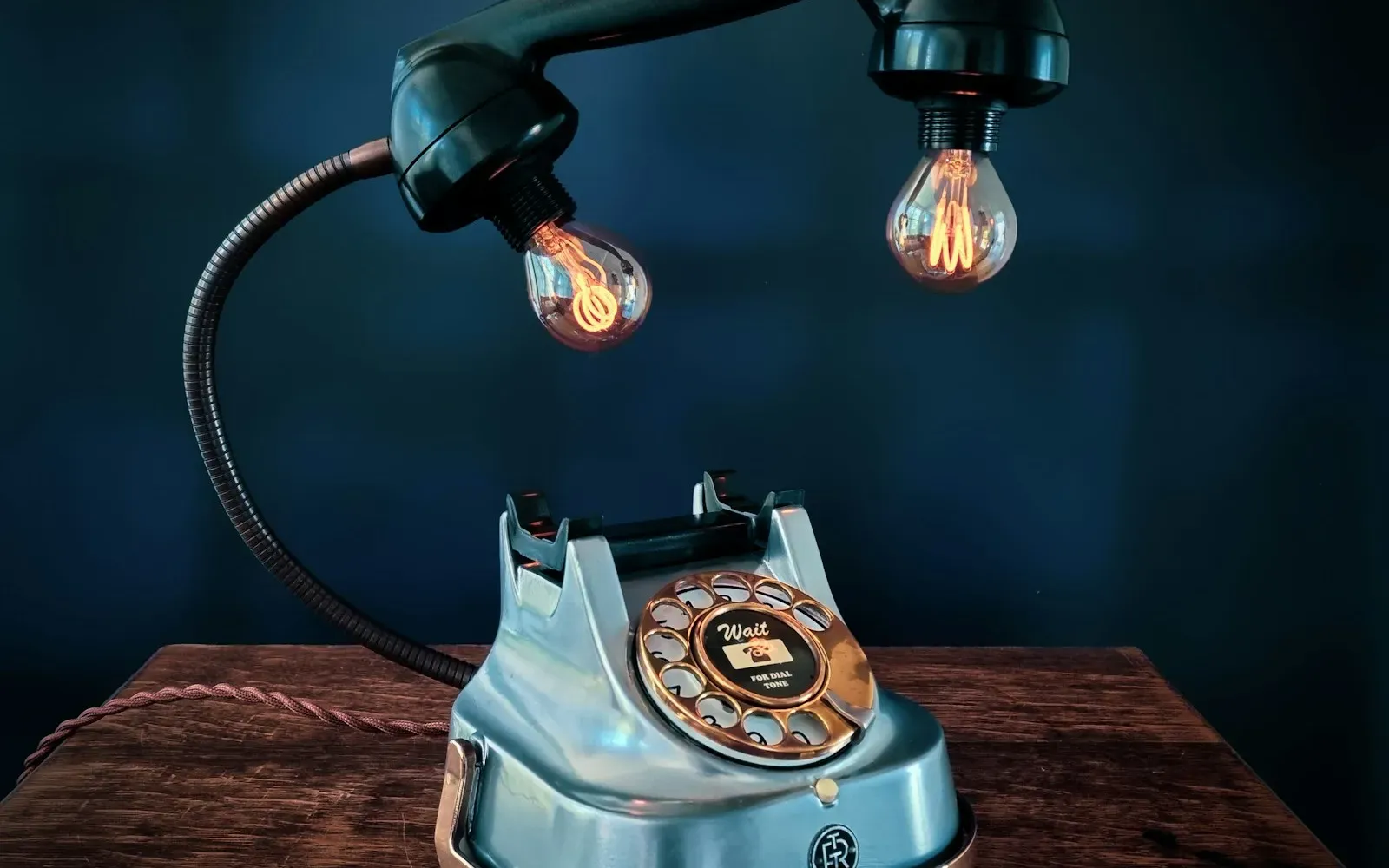 Altes Wählscheibentelefon unter warm leuchtenden Glühbirnen – Telefonsex Ideen
